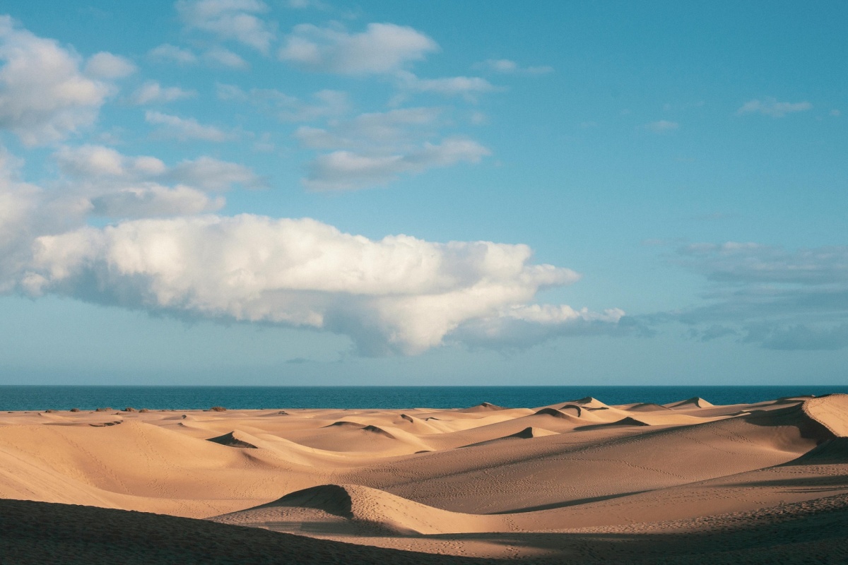 Playa de Maspalomas al atardecer con las dunas y el océano Atlántico de fondo